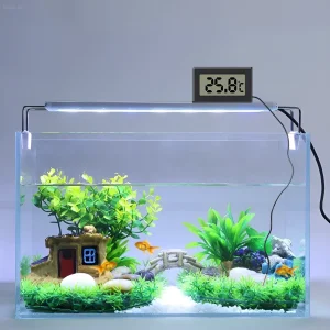 Изображение небольшого аквариума с золотыми рыбками, декорациями и термометром, показывающим 25.8°C. Подходит для иллюстрации оптимальной температуры для тропических рыб.